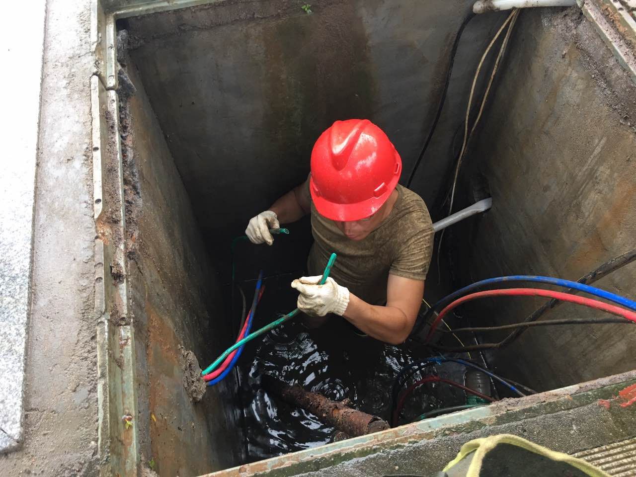 图为为了修复南津港大堤路灯线路故障,维护工人邓峰冒雨跳入检修井